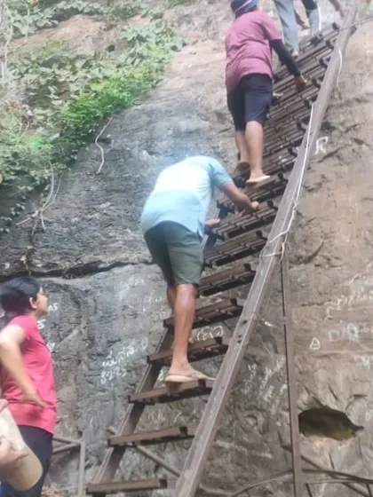 Trekkers climbing a rustic ladder to enter one of the caves. This trek involves some climbing and crawling, making it more adventurous.