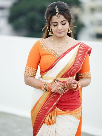 The full look, showing how the minimalist mehendi complements her beautiful orange and white saree without overpowering it.