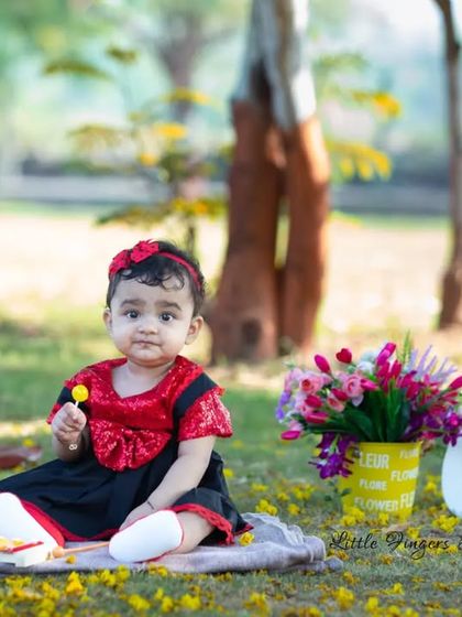 A sweet setup for a sweet first birthday girl. The combination of the 'One' sign, a picket fence, and a field of flowers creates a lovely scene for a milestone portrait.