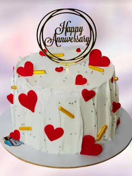 A simple yet festive anniversary cake covered in red hearts. The clean white base makes the red hearts pop, creating a classic symbol of love.