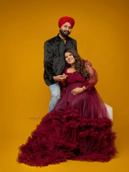 A variation of the seated pose against a solid yellow background. This image captures a formal yet warm interaction, showcasing the beautiful ruffled gown.