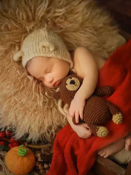 A perfectly cozy and sleepy newborn, nestled with a tiny teddy bear. We use soft textures, warm tones, and simple props to create a safe and adorable setting, highlighting the baby's peacefulness during these first few weeks.
