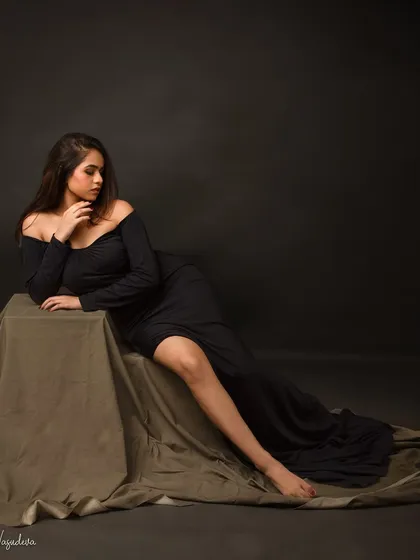 The elegance of a black dress. This classic pose highlights her graceful lines and thoughtful expression, creating a portrait that is both beautiful and divine.