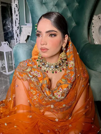 The side-swept hair is beautifully accented with a green-jeweled passa, adding a touch of contrast and elegance.
