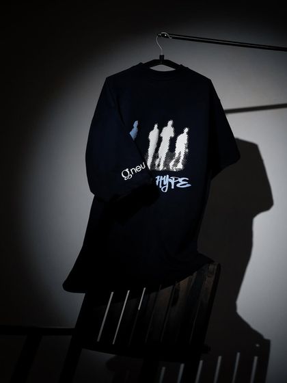 A moody shot of a black graphic tee on a hanger, with a single spotlight creating a dramatic, high-contrast look.