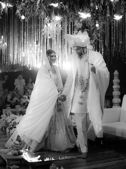 A timeless black and white shot of the couple after their pheras. The background of hanging floral strings and lights adds texture and depth to this beautiful moment.