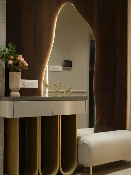 The entrance sets the tone for the entire home. I designed this foyer to be a piece of sculptural art, using a fluid, asymmetrical mirror with soft backlighting against rich wood paneling. The console's arched golden base is a statement of modern grandeur, creating a welcome that is both opulent and captivating.