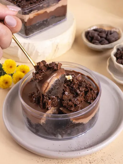 The perfect spoonful. This action shot of a spoon digging into a layered chocolate tub dessert is designed to highlight its creamy, rich texture and make you want a bite.