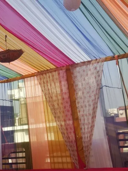 A closer view of the colorful ceiling draping we do for home functions. The light, flowing fabrics in various colors create a joyful and celebratory atmosphere, even in a simple outdoor space.