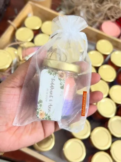 This shows our ombre candle packed in a sheer white potli bag. It's a simple, beautiful, and budget-friendly way to present your wedding return gifts.