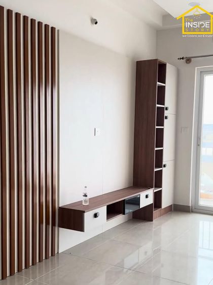 A clean and modern TV unit design featuring a combination of wood-grain laminate and white cabinets, with vertical fluted paneling adding texture and visual interest.
