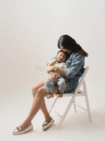 There is a universe of comfort in a mother's arms. This simple, elegant studio portrait shows a mother holding her son, their quiet connection and his happy smile being the central focus.
