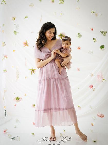 A slightly different pose from this floral session, this image captures a tender moment as the mother holds her baby's hand, surrounded by a cascade of petals.