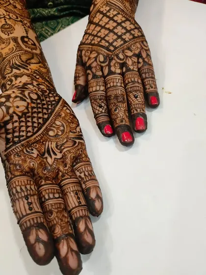 The bright red nails provide a beautiful contrast to the dark henna, a detail to consider when photographing your work.