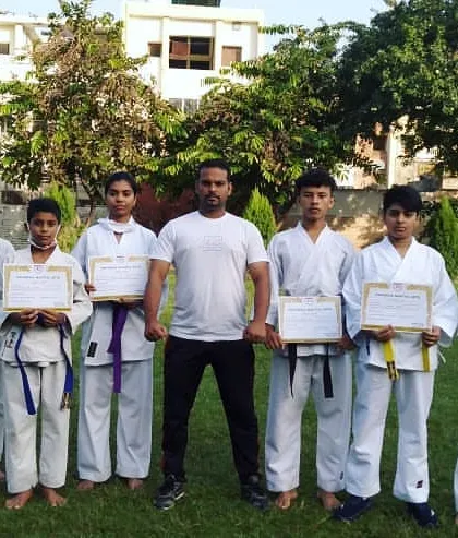 A group of students proudly displaying their certificates after passing their belt test. You can see different belt colors, from yellow to purple, showing their progression.