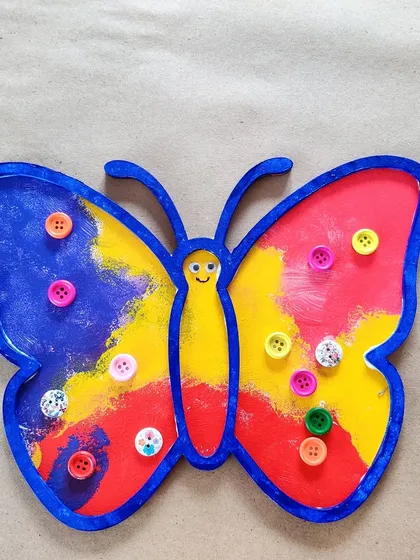A beautiful butterfly tray painted with bright colors and decorated with buttons. This was made by a toddler as a gift for her aunt.