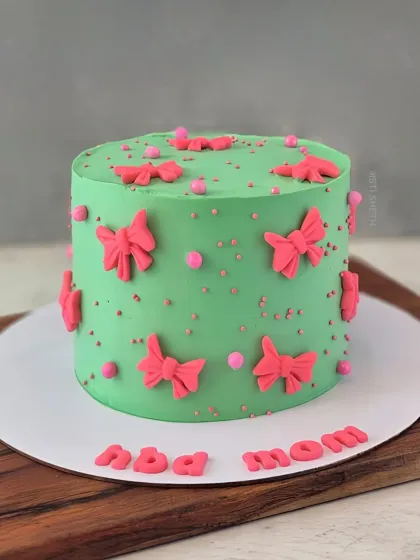 A cute and colourful cake for mom, decorated with green whipped cream and bright pink fondant bows.