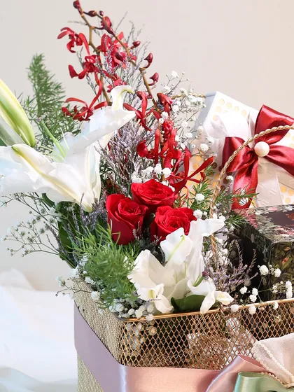 A close-up of the floral arrangement in the golden Mother's Day basket, highlighting the fresh red roses and delicate white lilies.