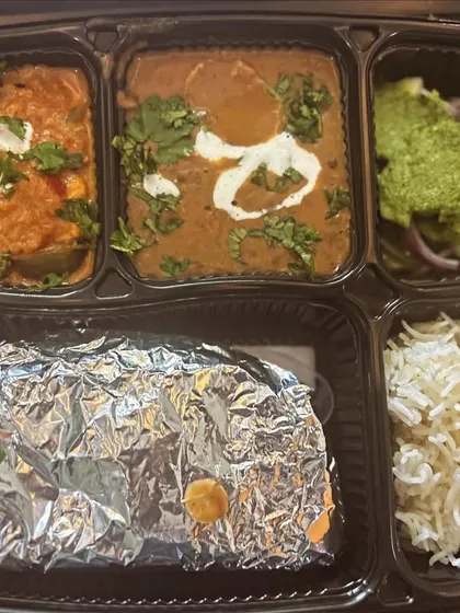 A close-up of a premium thali featuring Dal Makhni and Kadai Paneer. The fresh cream garnish on both dishes adds a touch of richness.