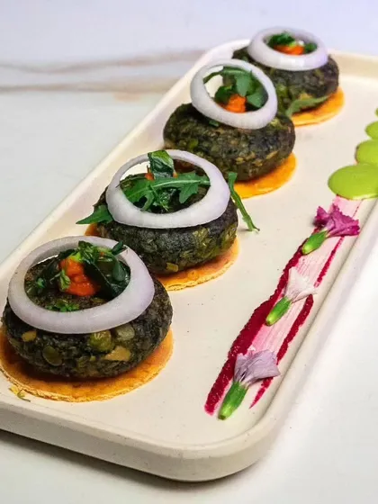 Another take on our Hara Bhara Kabab, artistically plated with onion rings and edible flowers, showing our attention to presentation.