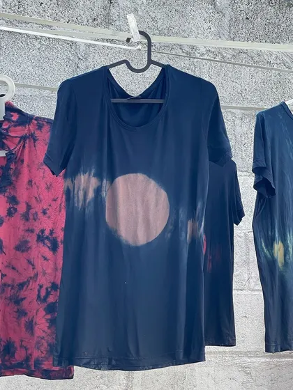 A few examples of re-dyed t-shirts hanging to dry. Each one tells a different story through its unique tie-dye patterns and colors, all achieved using non-toxic, plant-based dyes.