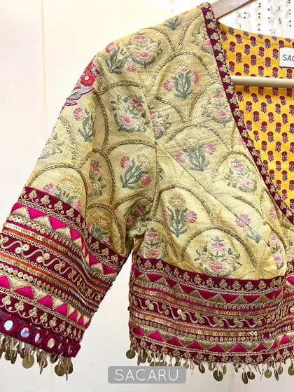 An artistic expression through fabric and embellishment. This vibrant patchwork blouse combines different prints and is finished with intricate hand embroidery using brass sequins and mirror work.