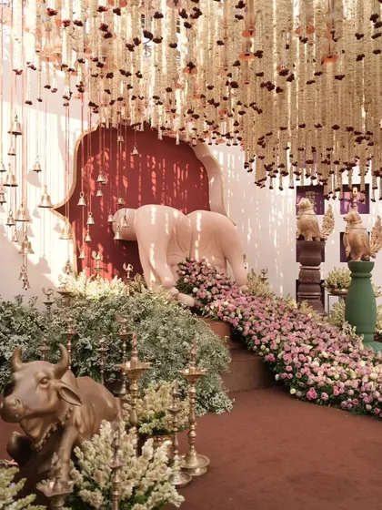 A stunning decor element featuring a sculpture of Nandi, the sacred bull, adorned with a river of pink flowers, under a ceiling of hanging bells. This is how I infuse spirituality and artistry into my designs.