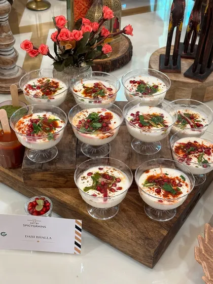 Cool and refreshing Dahi Bhalla cups, individually portioned for easy serving at a festive gathering. Garnished with pomegranate seeds and spices, they are a classic crowd pleaser for any celebration.
