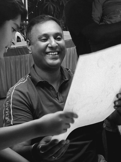 Another angle of a happy client examining his new caricature, showcasing the positive interaction.