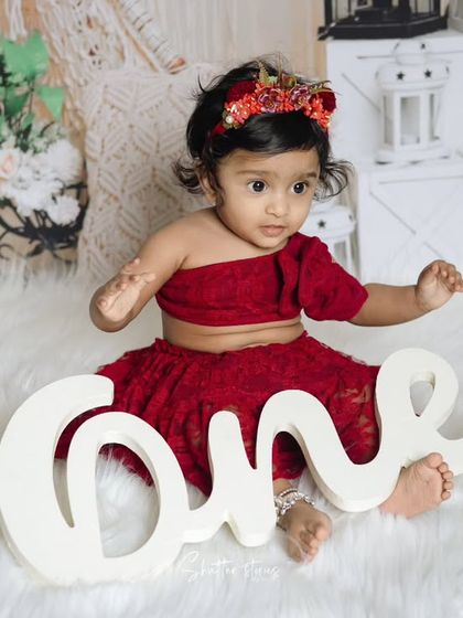 This little girl sits beside a "One" sign, marking her very special first birthday milestone.