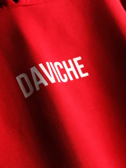 A close-up detail shot of the "DAVICHE" logo on the red hoodie. Highlighting fabric texture and branding details helps communicate the quality of the garment.