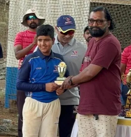 A U-14 player receives his individual award during the final presentation ceremony, surrounded by coaches and teammates.
