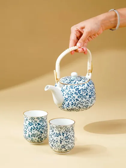 A floating shot of a hand holding a teapot, seemingly pouring into cups below. This creative composition is eye-catching and artistic.