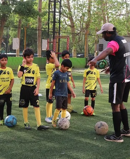 A coach gives instructions to a group of young players before they start a new drill.