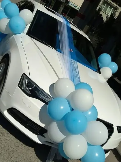 A simple and elegant car decoration with blue and white balloons and tulle fabric, perfect for a wedding or welcoming a baby.