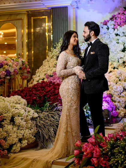 The couple stands amidst a sea of flowers, a romantic and grand setting for an engagement portrait.