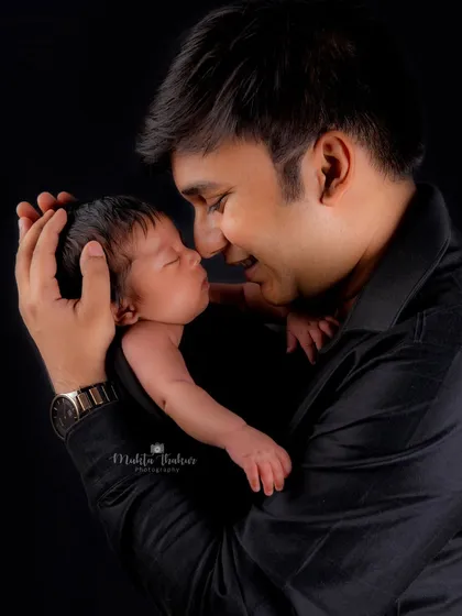 A father's gentle touch and loving gaze at his newborn daughter. This is a perfect example of a classic father-daughter portrait.