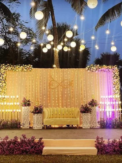 A simple yet elegant reception stage with a backdrop of cascading string lights. The purple uplighting and hanging lanterns add a touch of color and magic to the evening.