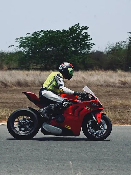 A side profile of a Ducati superbike on the track, showcasing the rider's focused posture and the bike's aerodynamic design at speed.