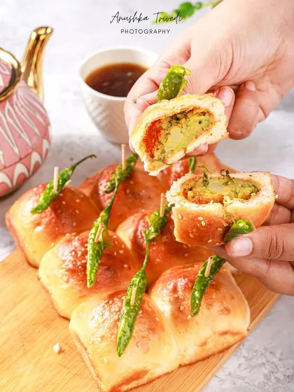 A modern take on vada pav, with stuffed buns arranged together. The action of breaking one open reveals the delicious filling, making it instantly craveable.