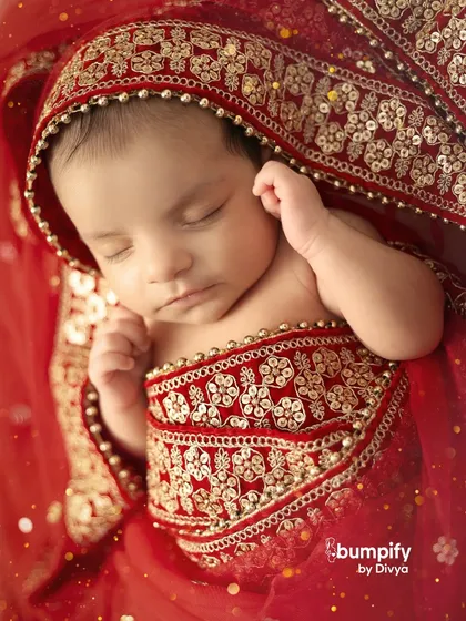A close-up on the newborn's peaceful face, framed by the intricate gold embroidery of the traditional red outfit. These details make the portrait extra special.
