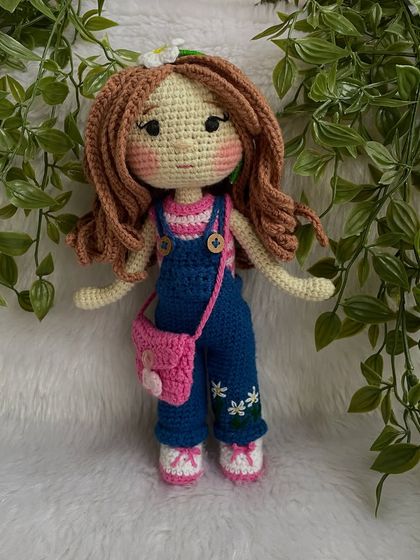 A closer look at the doll in her first outfit. The details on the overalls, like the little embroidered daisies, make her extra special. The clothes are designed to be easy for children to put on and take off.