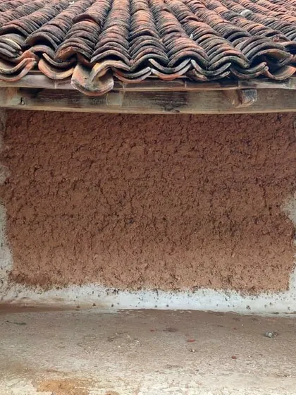 A patch of fresh mud plaster applied over an older wall. This technique is used for both construction and repair, showcasing the ease of maintenance and the forgiving nature of earthen materials.