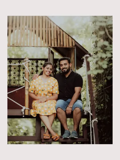 A sweet portrait of a couple sitting in a rustic treehouse structure, a unique and charming pre-wedding location.