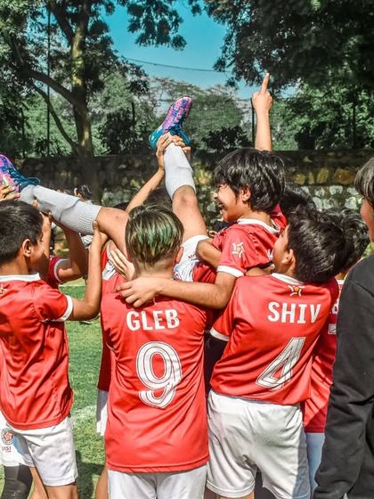 A team lifts their player in the air to celebrate a victory in the finals. A true display of camaraderie.