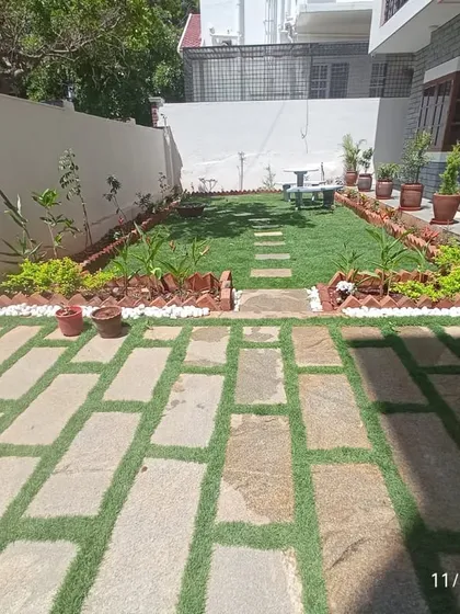 A complete residential backyard makeover we recently completed in Bangalore. The project included installing a new lawn, creating a stone paver patio with artificial grass inserts, and lining the space with neat garden beds and potted plants.