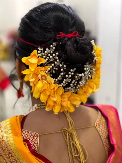 Another view of this intricate floral bun. The addition of a pearl-studded accessory adds a touch of glamour to the traditional hairstyle.