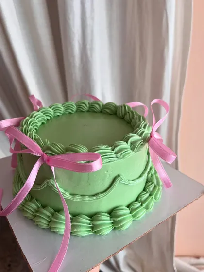 A vibrant take on the coquette style. This cake features bright green buttercream with pink ribbons, creating a fun and playful contrast.
