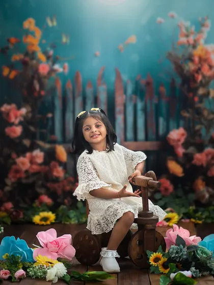 Big sister taking the lead on the wooden tricycle. Our garden theme is perfect for capturing playful sibling interactions.
