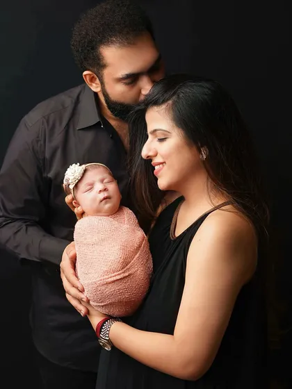 A new family portrait with a beautiful, soft light. The parents' gentle hold and loving expressions tell a story of a new chapter beginning.